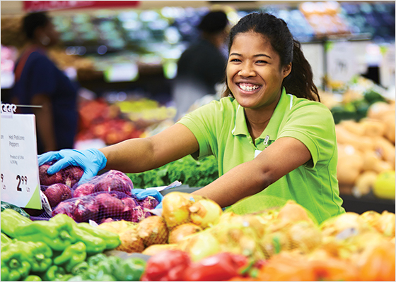 FreshCo employee stocking produce tables with onions.